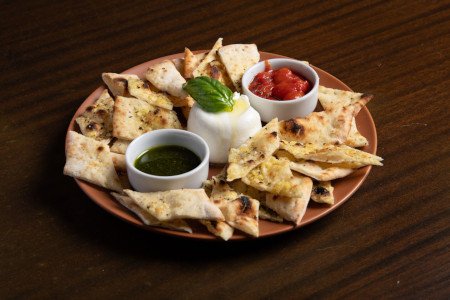 Burrata cremosa, tomates confitados, pesto genovese e tapenade de azeitonas pretas.
